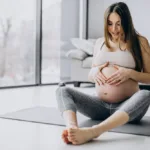 a pregnant woman sitting on a yoga mat